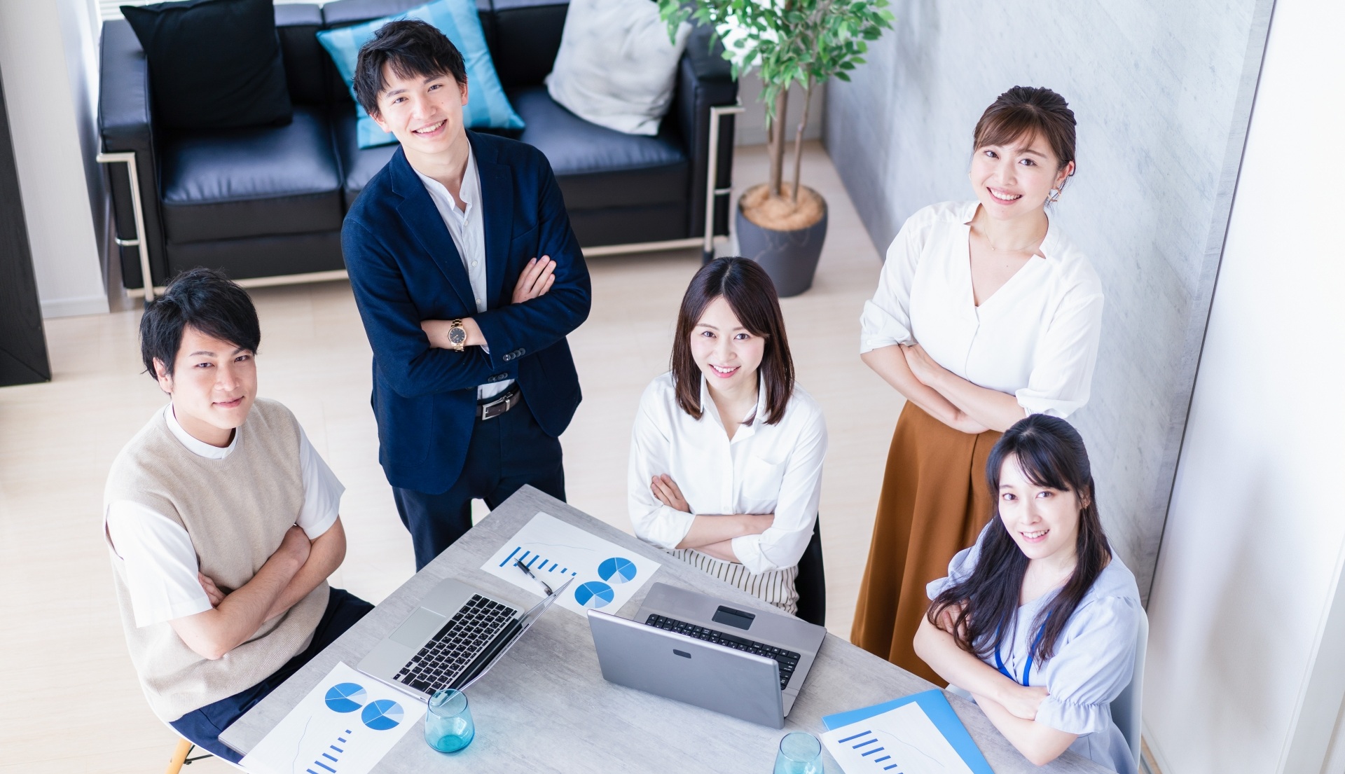 腕を組みほほ笑みながら上を見上げる社員５名
