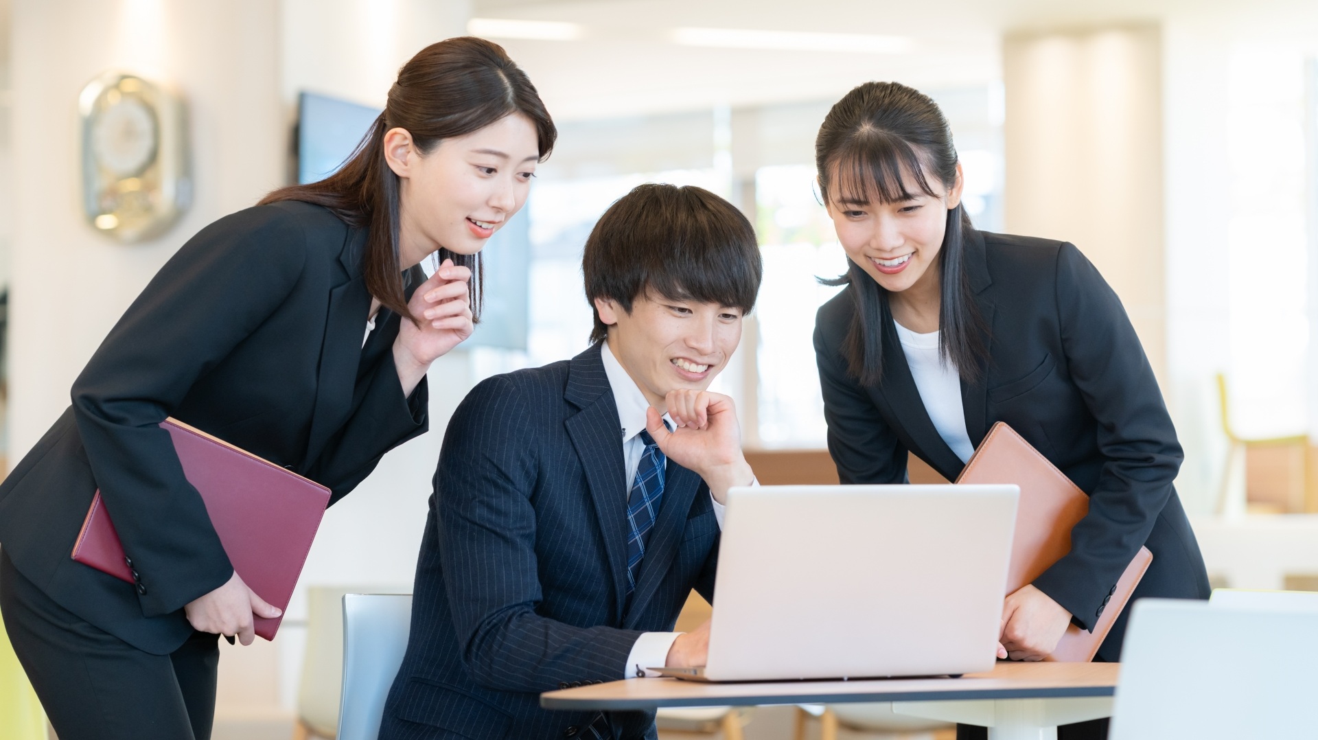 1つのPCを覗き込み談笑する社員3名