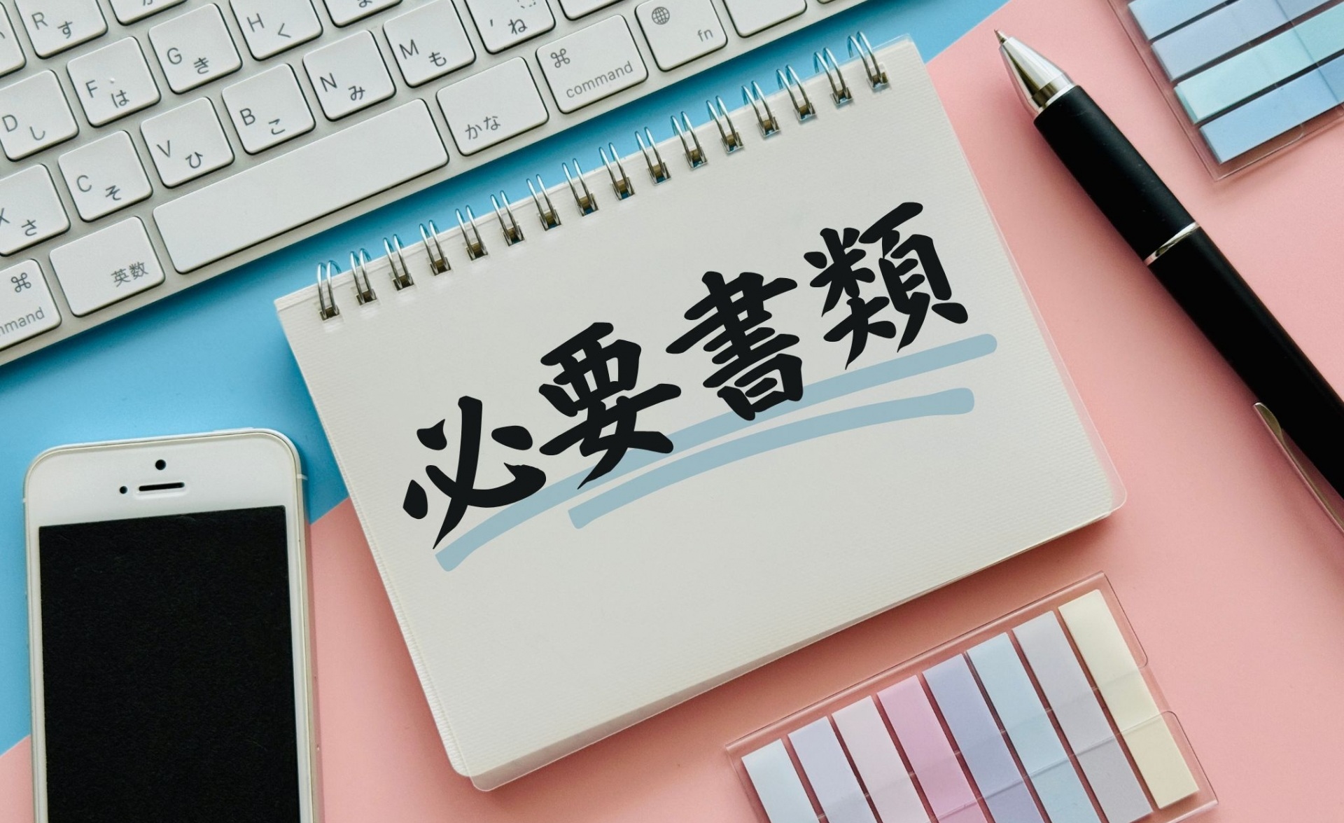 必要書類と書かれたノート、スマホ、文房具