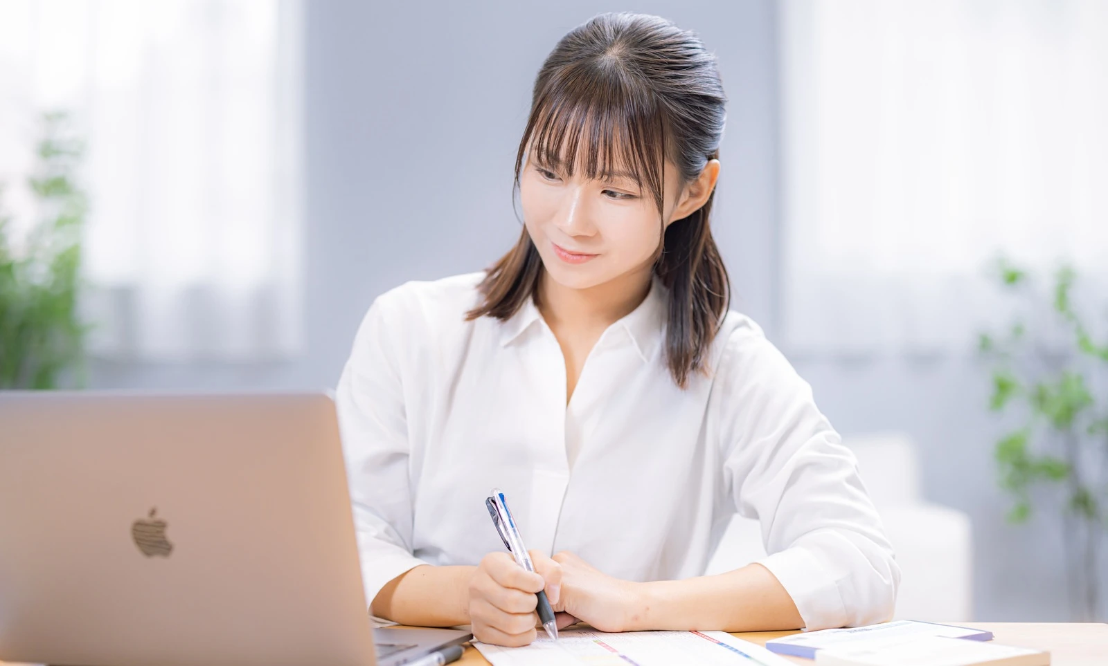 PCを見ながらメモを取る女性