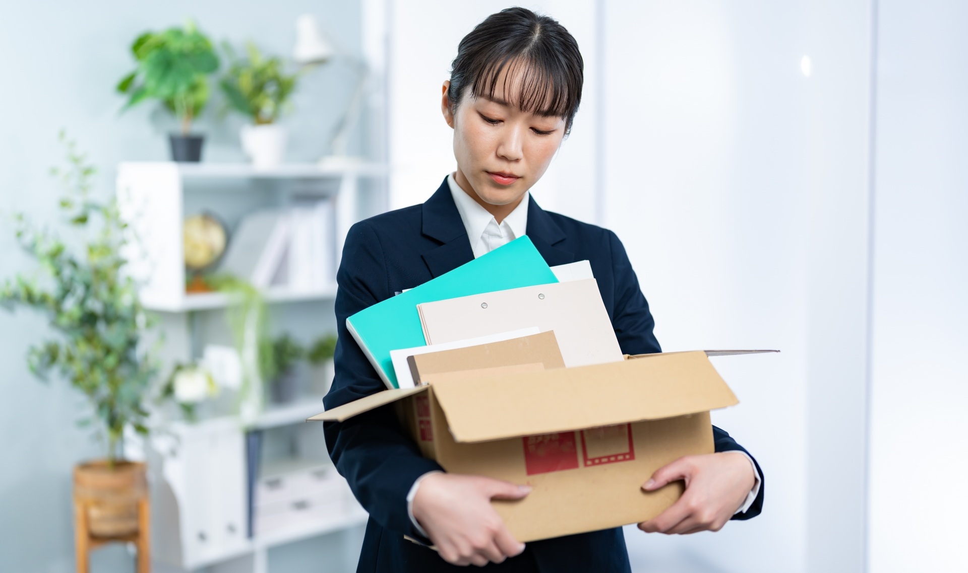 段ボールに荷物を入れて抱える女性