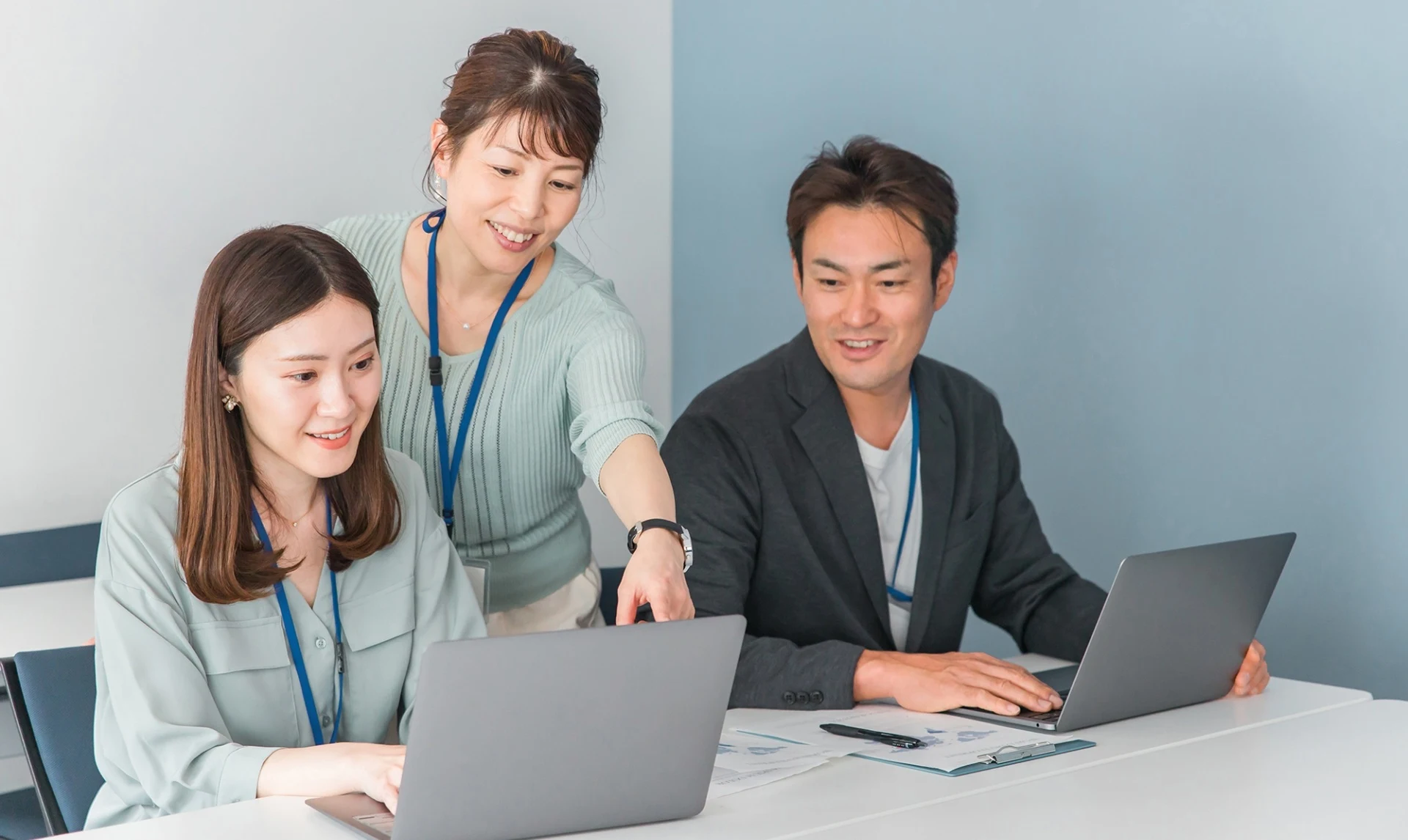 PCを指さし見ながら談笑する会社員3名