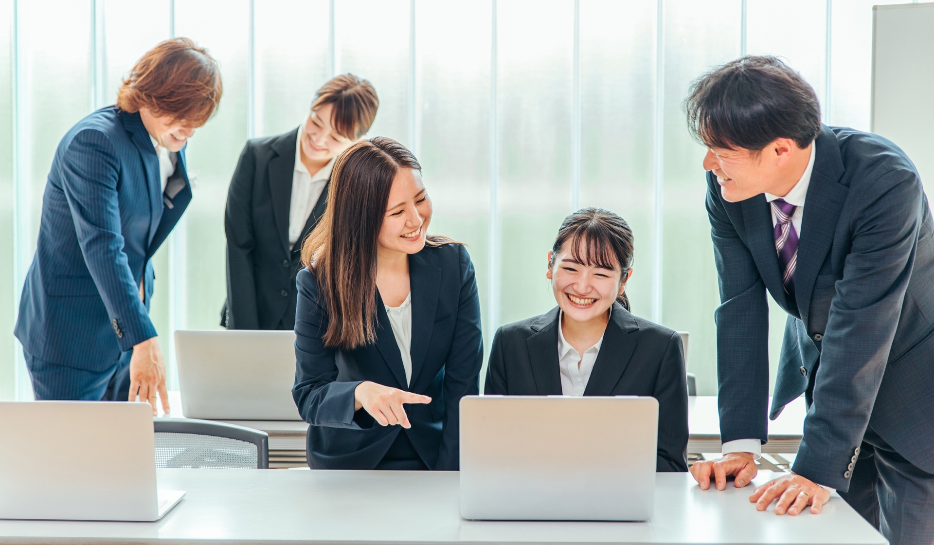 PCの前で談笑する会社員5名