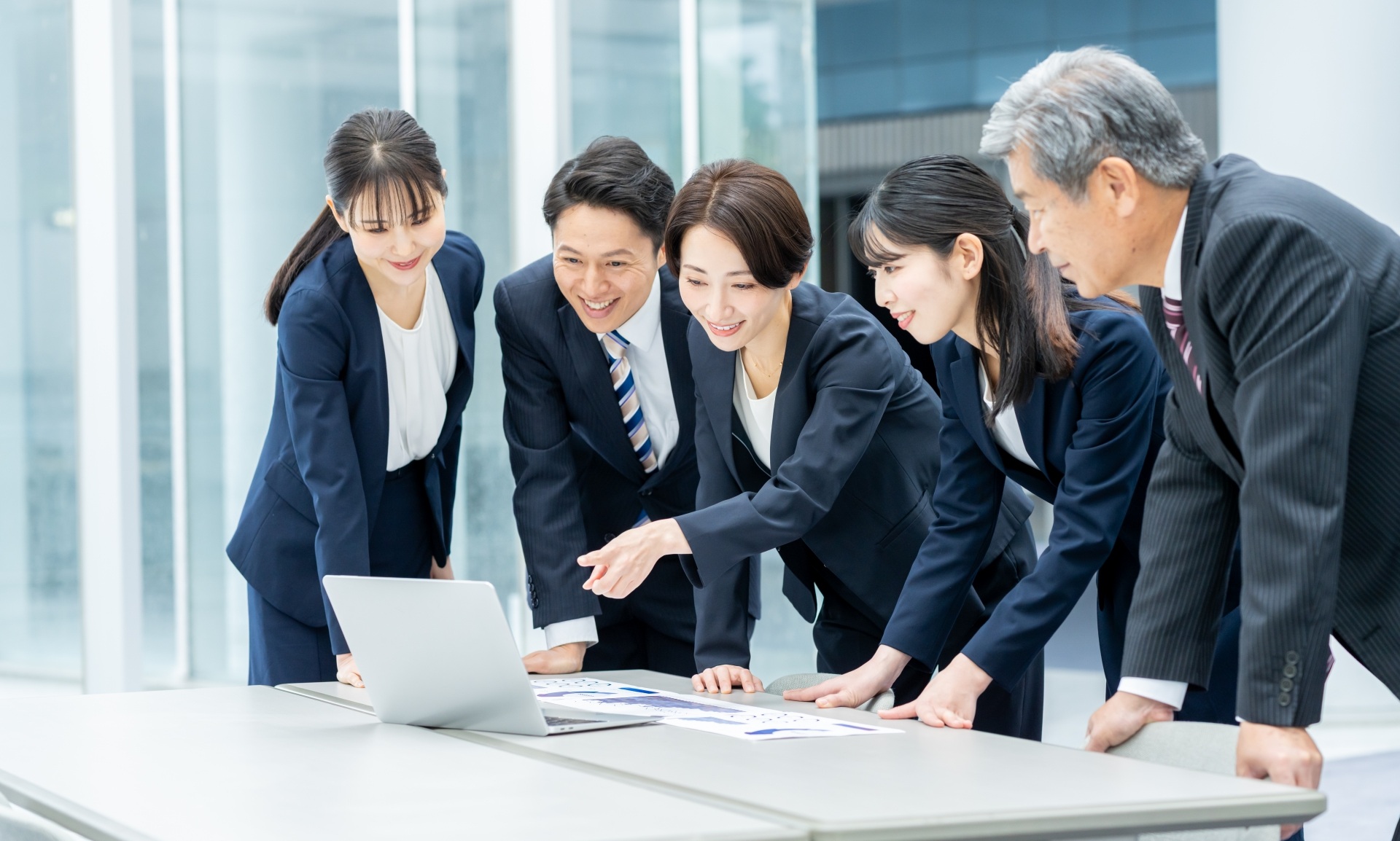 １台のPCを見ながら談笑する会社員５名