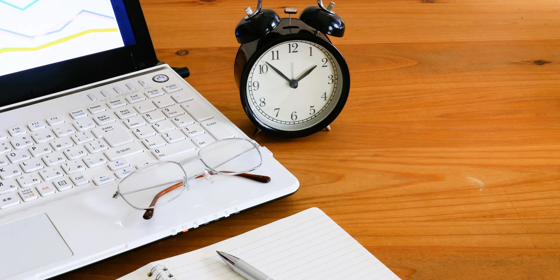 時計と眼鏡と文房具が机に並んでいる