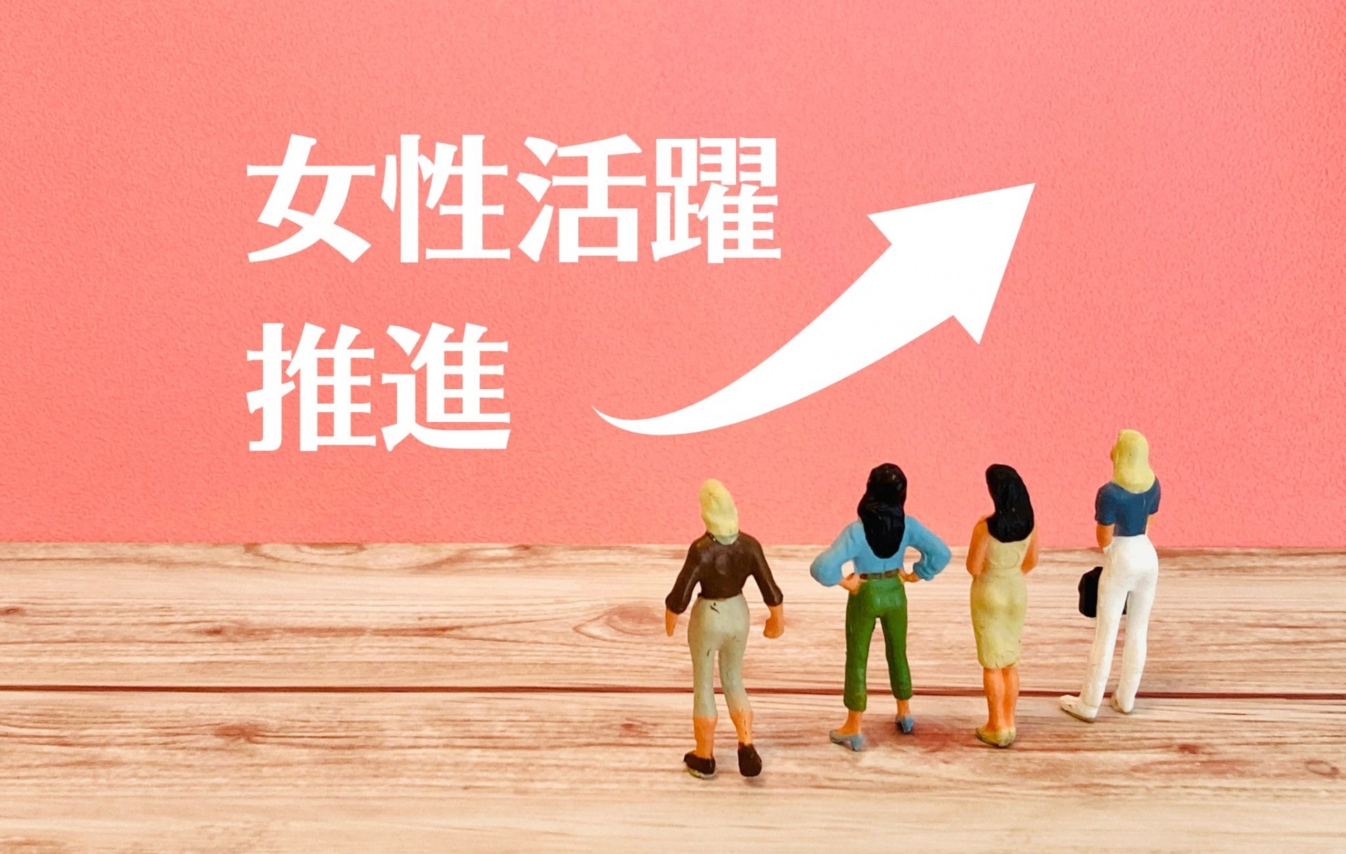 女性活躍推進と書かれた背景の前にミニチュアの人間がいる