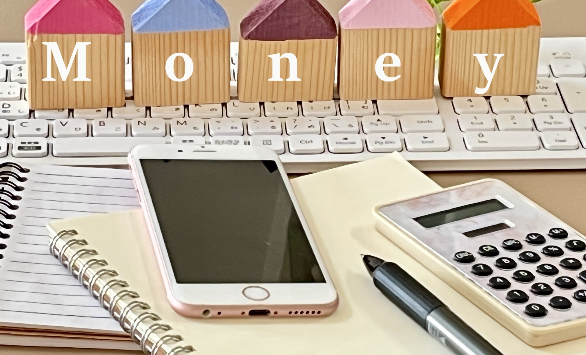 Moneyと書かれたブロック、電卓、文房具とスマホ