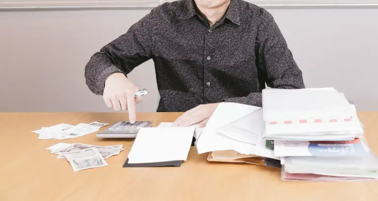 書類の山と電卓、紙幣