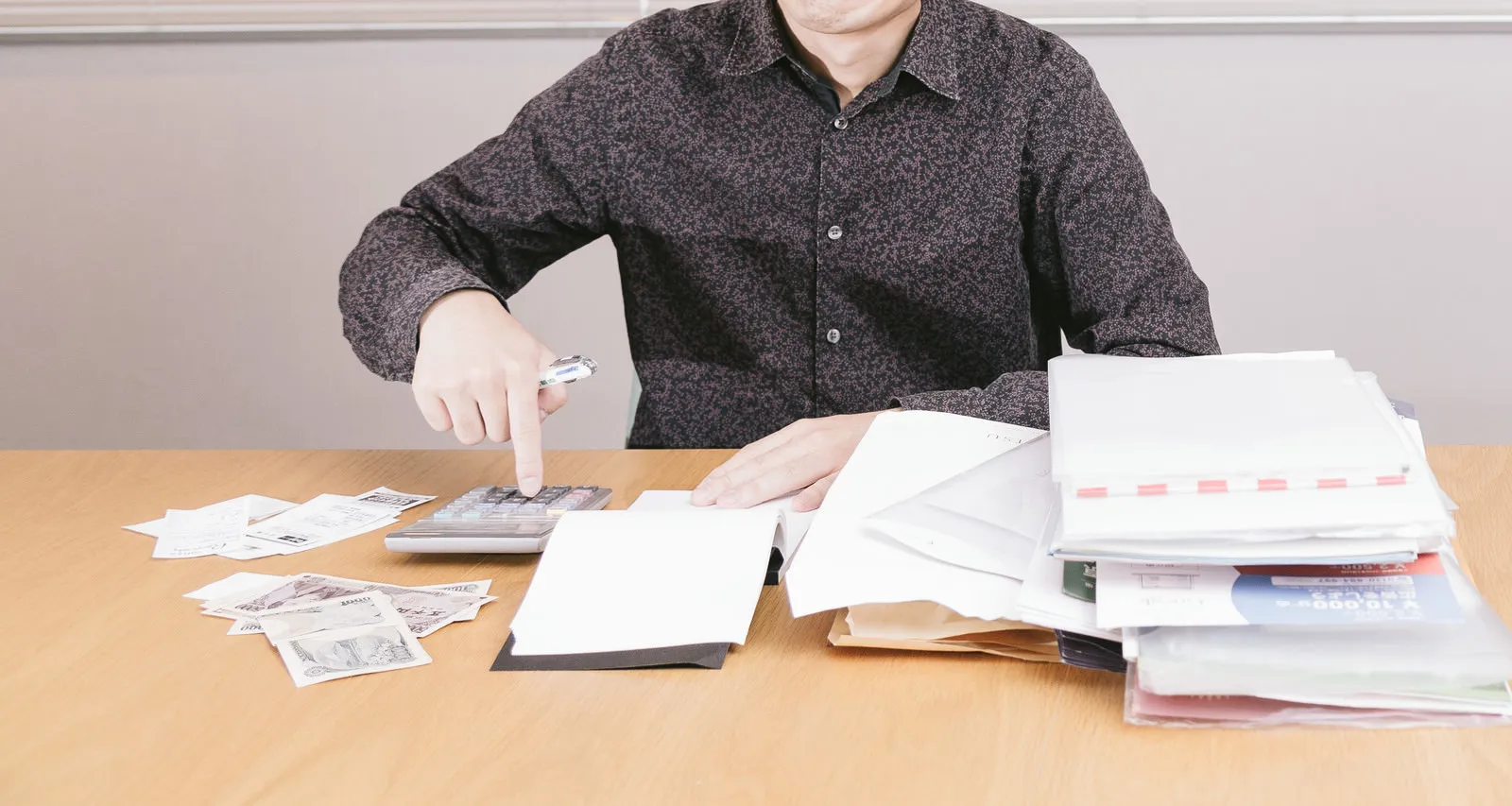 書類の山と電卓、紙幣