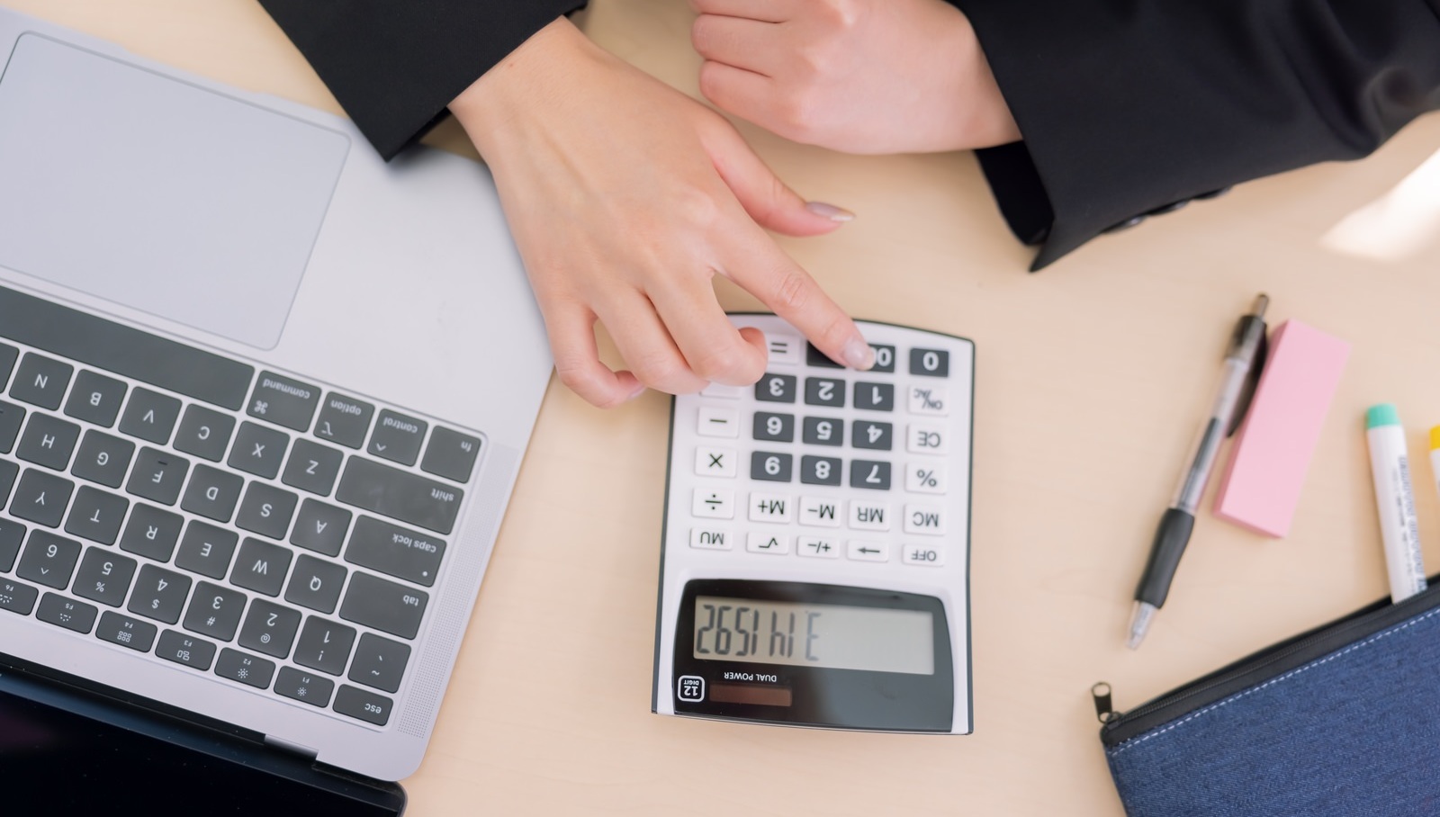 PCを傍らに電卓をたたく人間の手