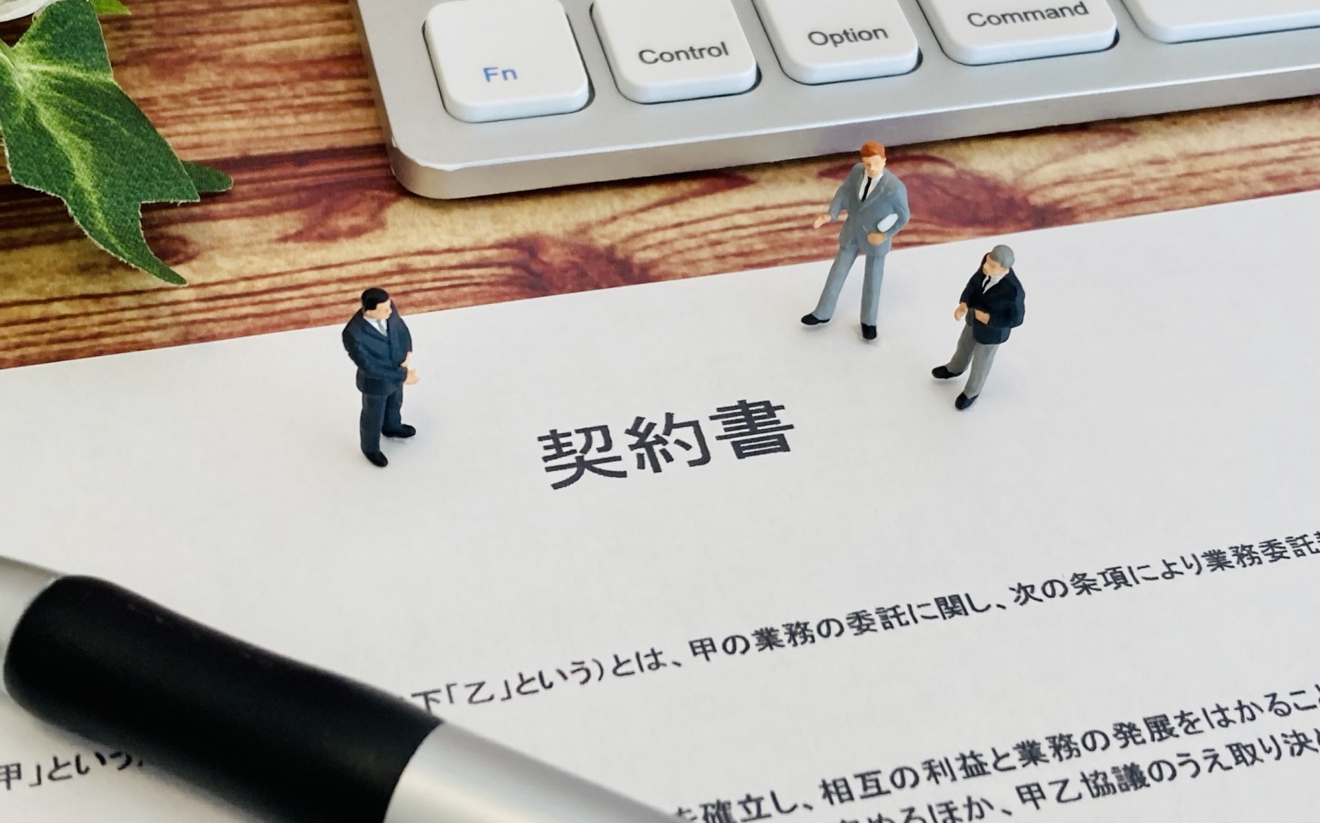 契約書と書かれた書類とミニチュアの人類