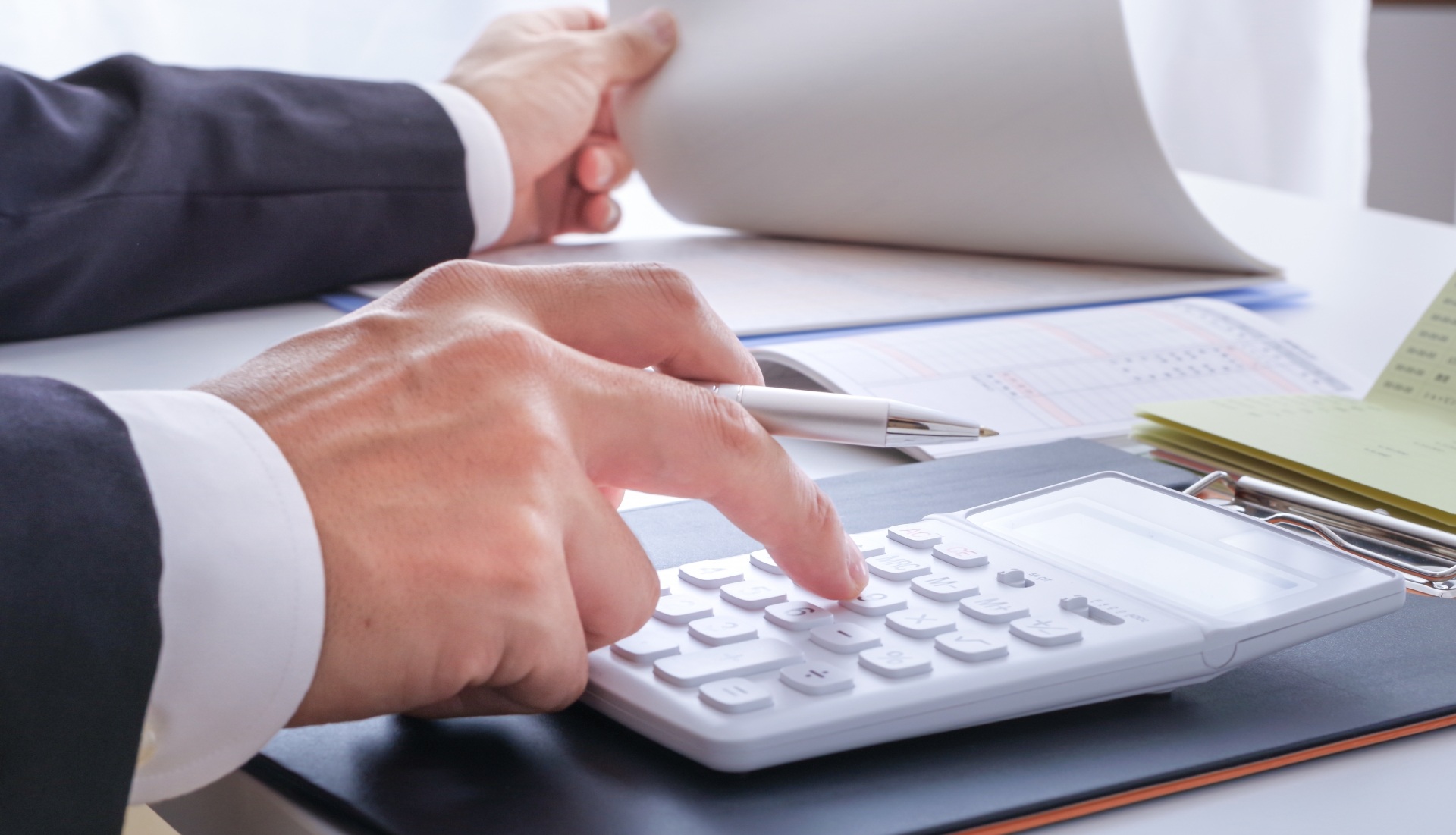 紙をめくりながら電卓を叩く手