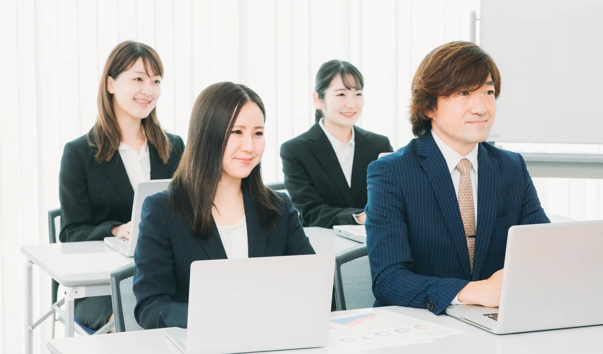 PCを机の上に置き前を見る社員名