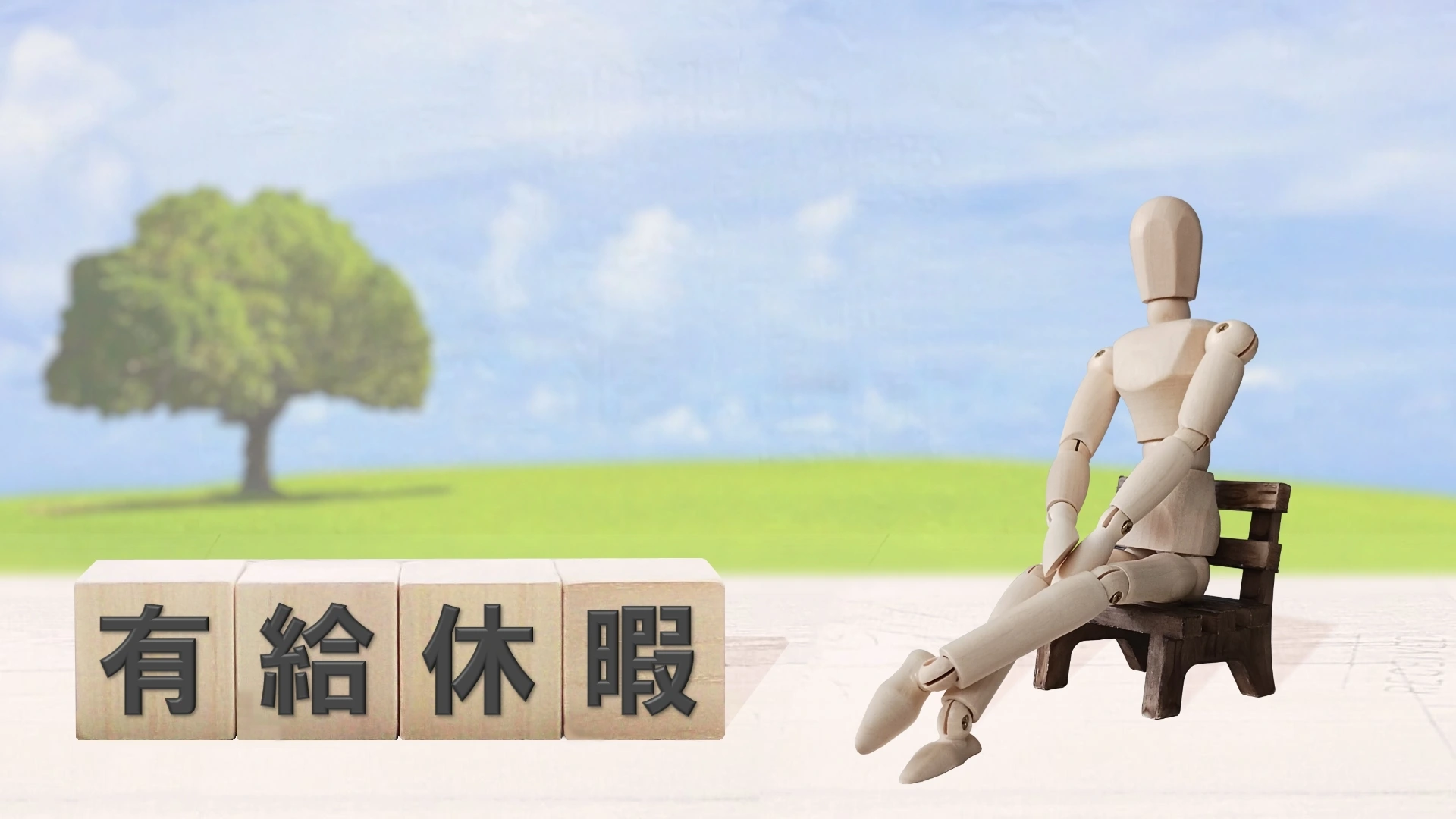 有給休暇と書かれたブロックと、野外を背景に椅子に座るミニチュア人形