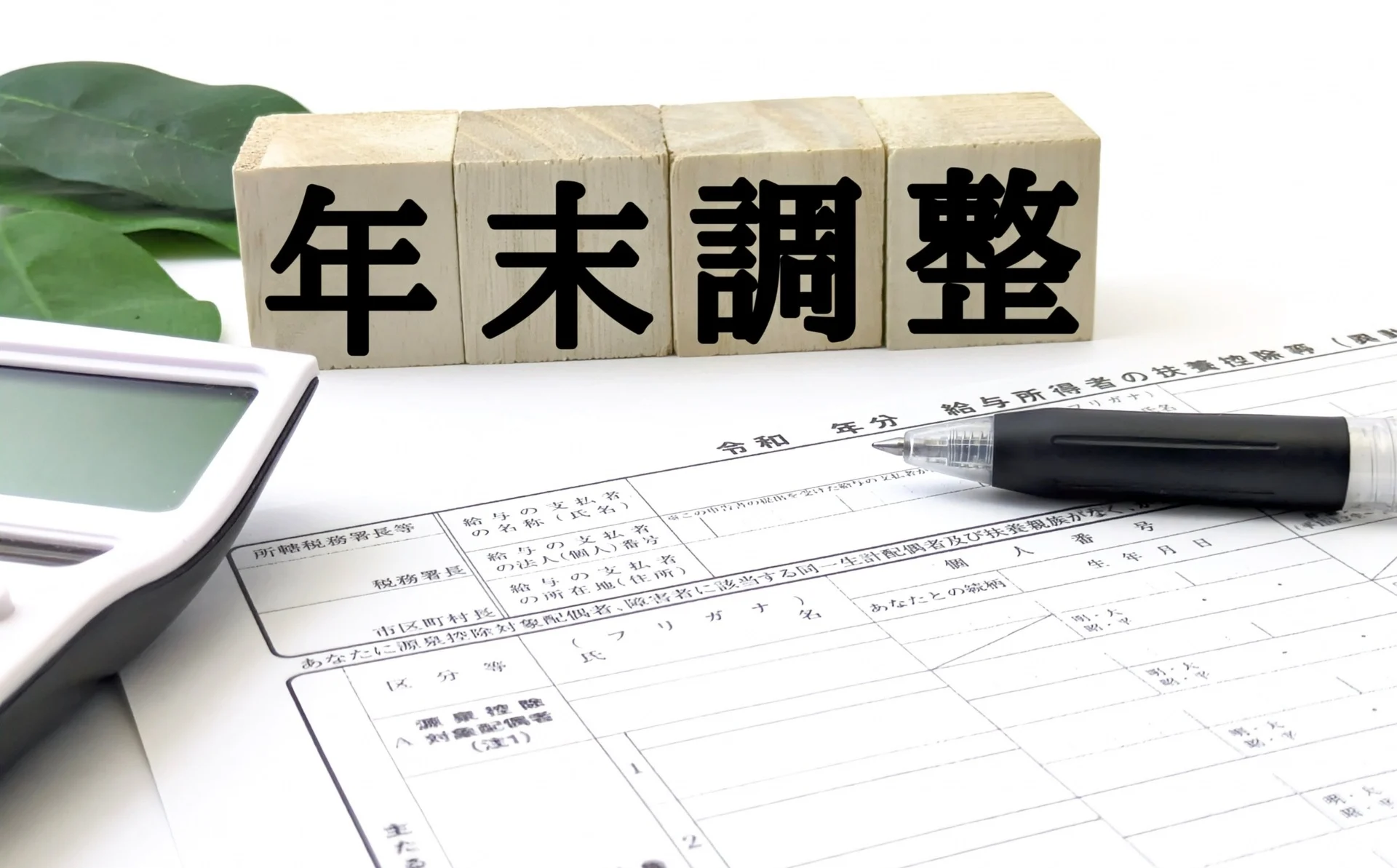年末調整と書かれたブロックと電卓、ボールペン、申告書